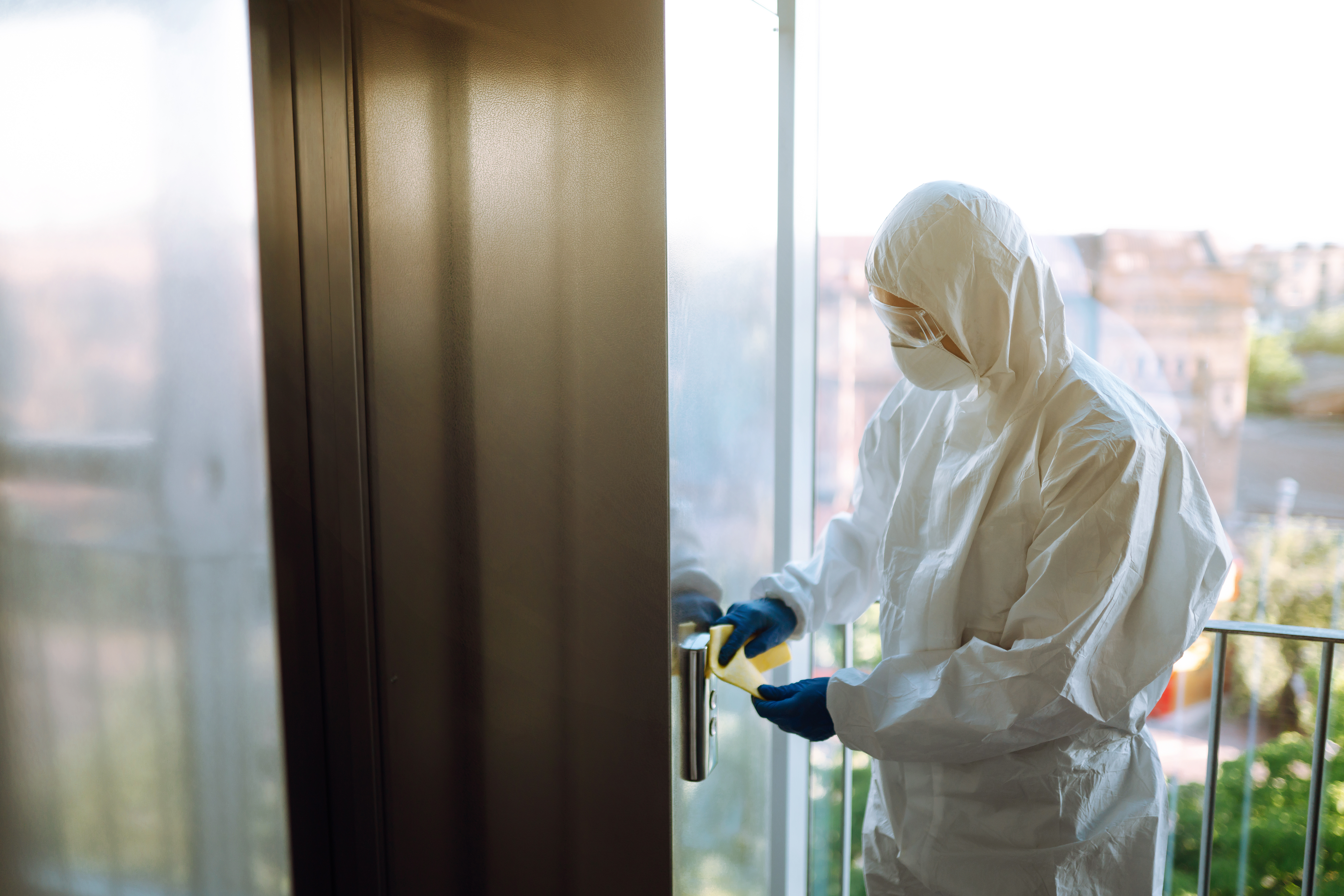 Worker in protective suit cleaning elevator buttons and doors