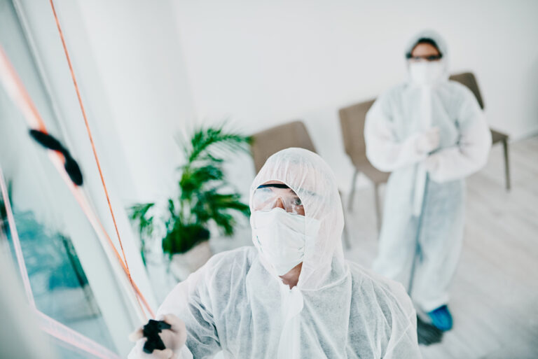 Worker in protective suit cleaning a window with a squeegee