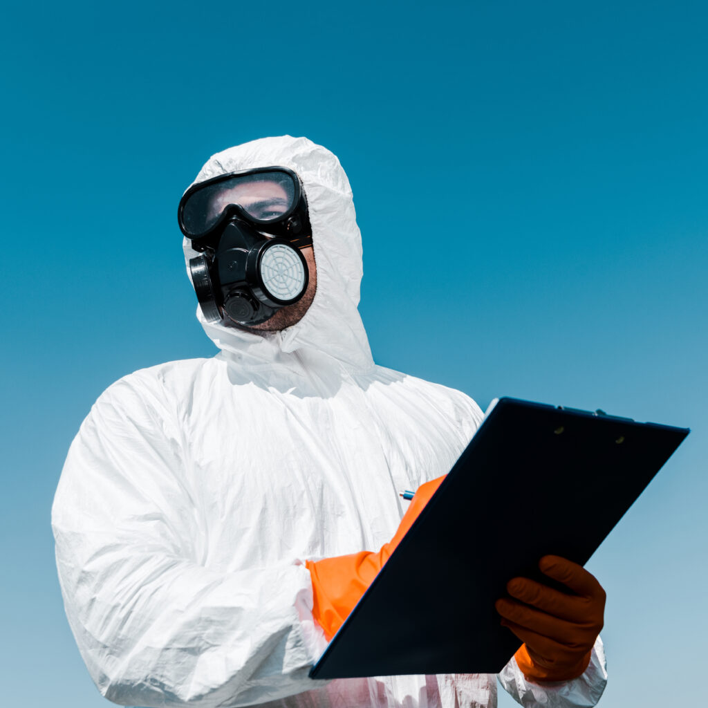 Worker in protective suit and respirator holding a clipboard