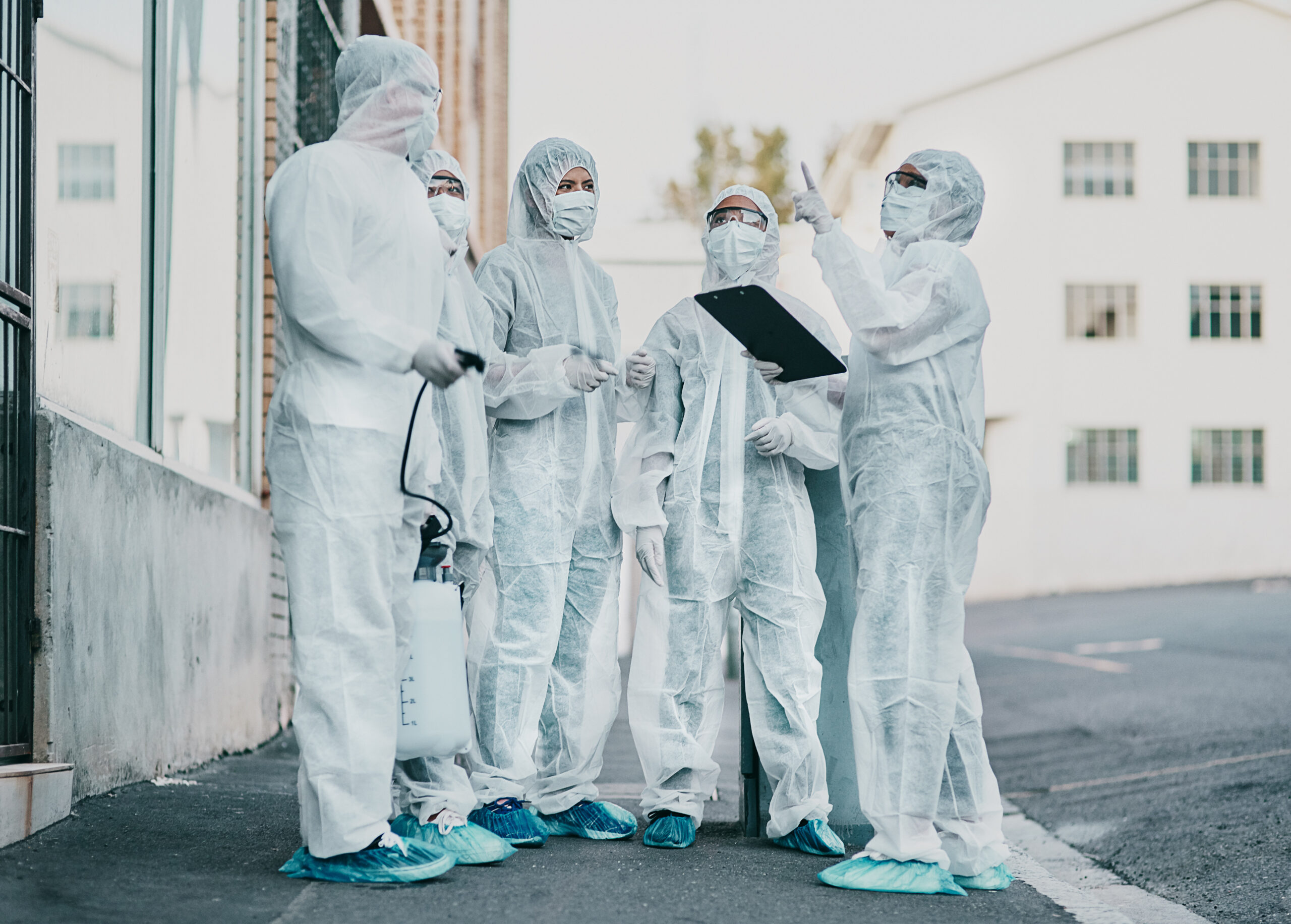 Group of workers in protective suits standing outdoors with a clipboard