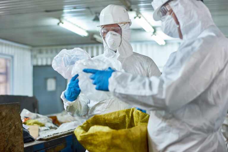 Workers in protective gear sorting plastic waste at a processing facility